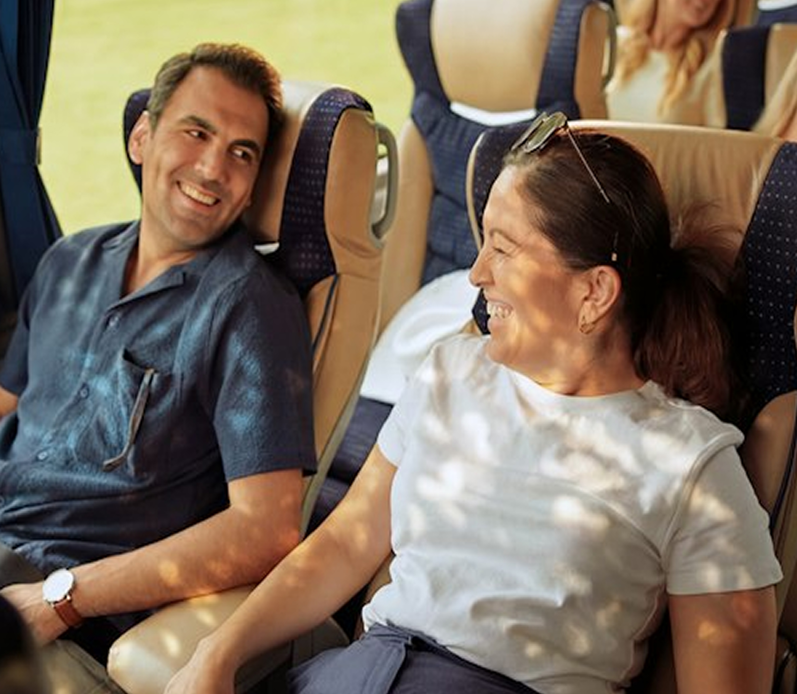 Two passengers smiling and chatting while seated comfortably on a Luxuria coach.